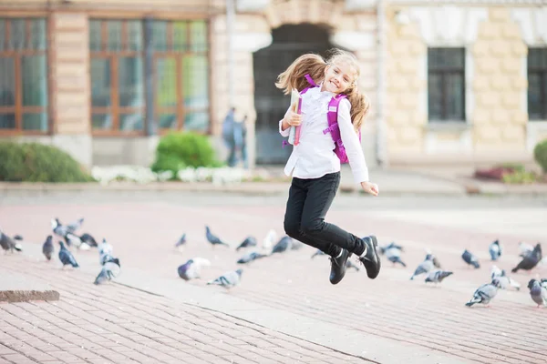 Colegiala saltando con una mochila y libro al aire libre. Concepto de educación y aprendizaje . — Foto de Stock