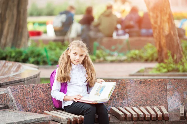 Schoolmeisje met een rugzak en boek buiten. Onderwijs-en Leerconcept. — Stockfoto