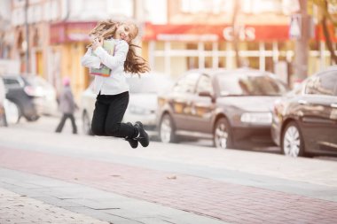 Bir sırt çantası ile atlayan liseli kız ve kitap açık havada. Eğitim ve öğrenme kavramı.