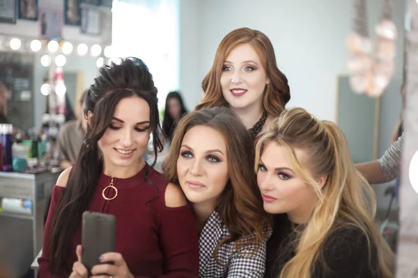 Cztery młode kobiety kobiety biorą selfie w lustrze w salonie piękności. — Zdjęcie stockowe