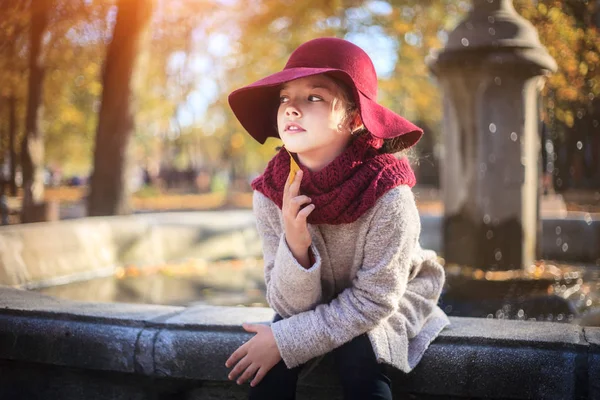 Fille en manteau classique et chapeau dans le parc d'automne près de la fontaine. Saison d'automne, mode, enfance . — Photo