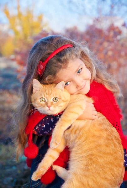 Portrét malé holčičky s červeným kocourem v dlaních na podzim. — Stock fotografie