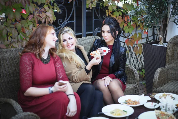 Three women drink coffee and eat pizza in a cafe. — Stock Photo, Image