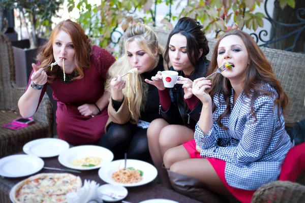 Four women drink coffee, eat pizza and pasta in a cafe. — Stock Photo, Image