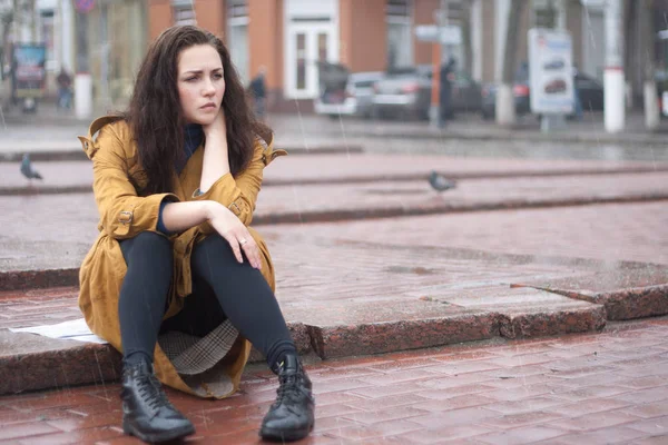 Smutna kobieta siedzi na zewnątrz jesienią w deszczowy dzień. — Zdjęcie stockowe