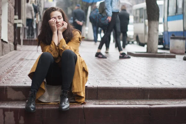 Ledsen kvinna sitter utomhus på hösten på en regnig dag. — Stockfoto