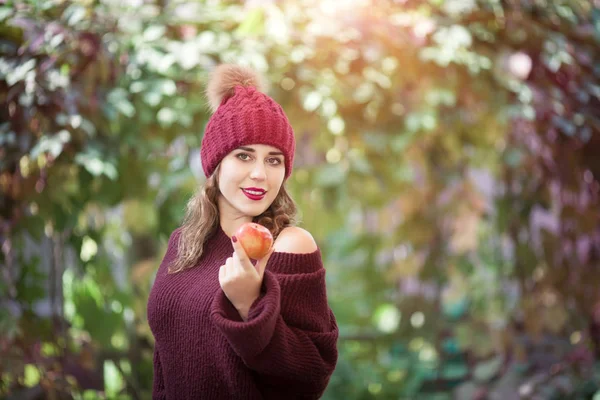 Retrato de estilo de vida feliz de uma bela jovem em um chapéu quente de outono com uma maçã na mão . — Fotografia de Stock