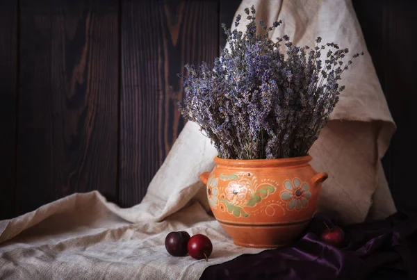 Stilleben med lavendel i en lerkruka och plommon på bordet. — Stockfoto