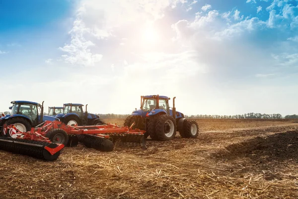 Vários tratores arados o campo, cultiva o solo para semear o grão. O conceito de agricultura . — Fotografia de Stock