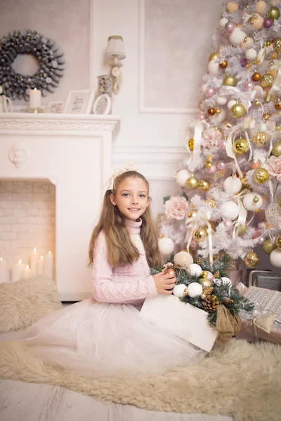 Beautiful little girl in a dress sitting near the Christmas tree. Winter holidays. Happy New Year — Stock Photo, Image