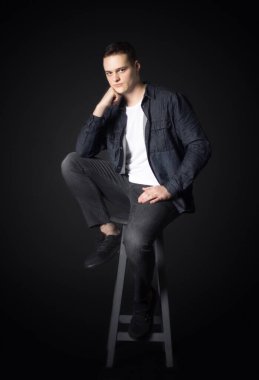 Stüdyoda siyah arka planda çekici bir adamın portresi. Genç, ciddi adam..