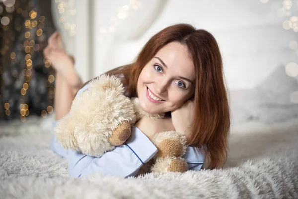 Junge schöne Frau im Schlafanzug im Schlafzimmer. Winterurlaub. — Stockfoto