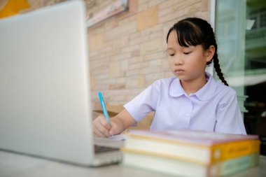 Covid-19 ve Bangkok Tayland 'daki Dust PM2.5 salgını nedeniyle okul kapalı olduğu için ilkokul öğrencisi evde ödev yapıyor.