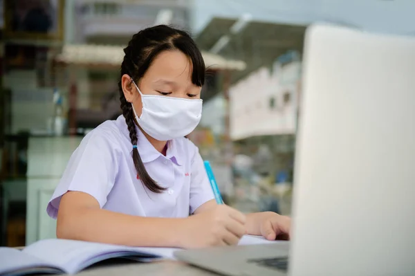 Junior Primary school girl Do homework at home Because the school is closed Due to the severe outbreak of the Corona virus Covid-19 and Dust PM2.5 in Bangkok Thailand