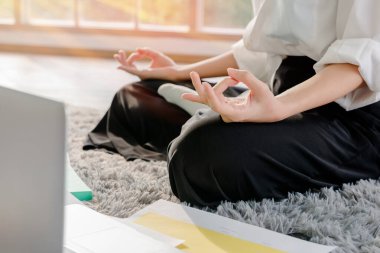 Evde elinde defterle çalışan bir kadın evde Lotus pozisyonunda meditasyon yaparak rahatlıyor. Coronavirus salgını sırasında, Covid-19