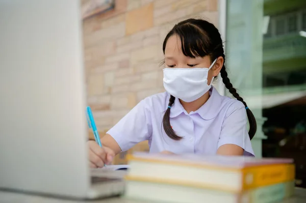 Covid-19 ve Bangkok Tayland 'daki Dust PM2.5 salgını nedeniyle okul kapalı olduğu için ilkokul öğrencisi evde ödev yapıyor.