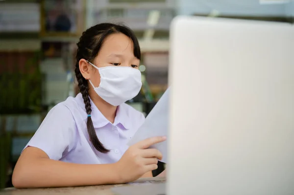 Covid-19 ve Bangkok Tayland 'daki Dust PM2.5 salgını nedeniyle okul kapalı olduğu için ilkokul öğrencisi evde ödev yapıyor.