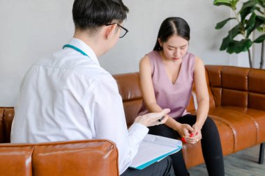 Akıl hastaları konsepti. Genç doktorun psikoloğu rapor yazıyor ve ofisteki kadın akıl hastalarıyla konuşuyor.