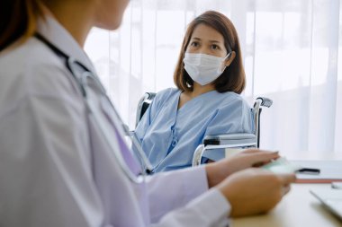 Tekerlekli sandalyedeki Coronavirus hastaları kadın doktorla konuşuyor. COVID-19 enfeksiyonu özel bir odada, özel bir odada, karantina odasında inceleniyor. Ofis doktoru ve koronavirüs hastaları