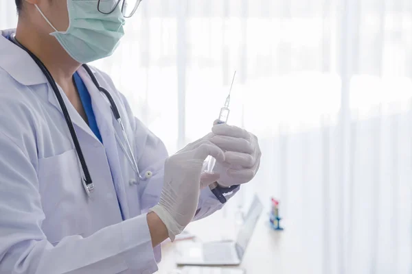 Bir doktor hastane ofisinde ilaç şırıngası kullanıyor. Coronavirus enfeksiyonu olan bir hasta, Covid-19..