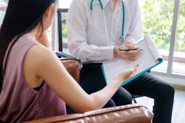 Akıl hastaları konsepti. Genç doktorun psikoloğu rapor yazıyor ve ofisteki kadın akıl hastalarıyla konuşuyor.