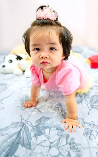 Güzel bir kız bebek oyun konsepti, pembe elbiseli bir bebek oyuncak ayı ve oyuncakla oynuyor çok mutlu komik ve Bangkok Tayland, Asya 'da yatakta gülümsüyor.