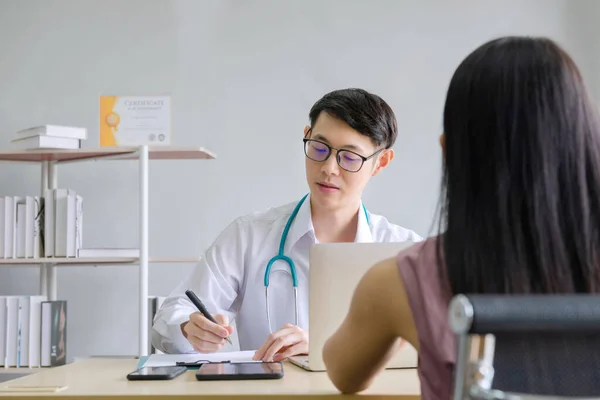Akıl hastaları konsepti. Genç doktorun psikoloğu rapor yazıyor ve ofisteki kadın akıl hastalarıyla konuşuyor.