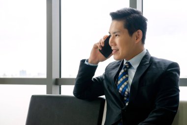 Yakışıklı, yetişkin, kendine güveni tam genç bir iş adamı yeni ofiste çalışıyor. Küçük bir finans şirketinde teknoloji ürünü akıllı telefon, tablet ve bilgisayar kullandı. 