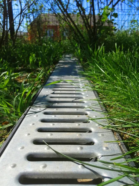 drainage systems. idea - building a house, storm taps. metal construction from the roof - sewer and grate on the ground for draining water closeup. sunny day, green grass