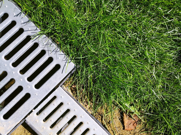 дренажные системы. Идея - строительство дома, штормовые краны. металлическая конструкция с крыши - канализация и решетка на земле для слива воды крупным планом. солнечный день, зеленая трава
