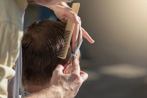 Die Hände eines Friseurs in Großaufnahme mit Schere und Kamm. Der Friseur schneidet einen Mann und macht einen Haarschnitt. horizontales Foto mit Textstelle. — Stockfoto