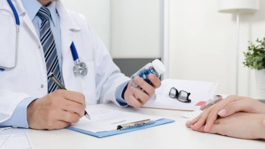 Doktor ve hasta ofisinde. Doktor reçete reçete. İlaç şişesi holding.