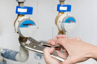 Yeni bir su sayacı teknisyen yükler. Mavi modern radyo su sayacı. Adam elini tutarak anahtarı.