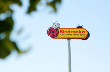 WROCLAW, POLAND - JUNE, 2018. Biedronka's logo on a pole against the blue sky. Biedronka is the largest supermarket chain in Poland and has over 2800 stores. clipart