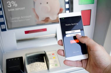 Bir kredi kartı kullanmadan bir Atm para çekmek. Bir telefon ile mobil bankacılık için bir giriş ekranı tutan kişi.