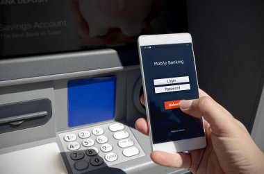 Bir kredi kartı kullanmadan bir Atm para çekmek. Bir telefon ile mobil bankacılık için bir giriş ekranı tutan kişi.
