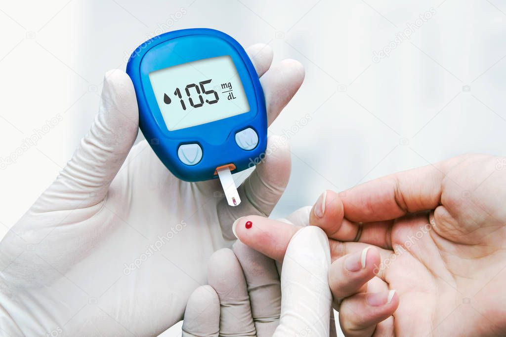 Doctor making blood sugar test in clinic for diabetes. Drop of blood on the finger