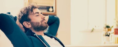 Genç adam eski püskü bir odada sandalyesinde dinleniyor.