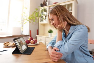 Kadın bir dijital tablet kullanarak görüntülü sohbet aracılığıyla adamla söz