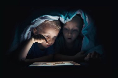Tablet bilgisayar karanlık bir odada iki çocuklu. Çocukların Internet kavramı içerikten karşı korunması