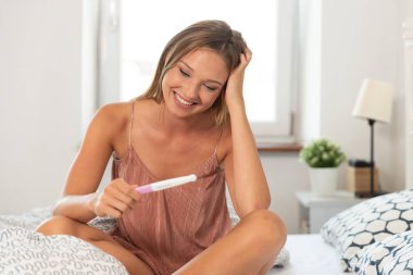 Genç mutlu kadın hamilelik testi sonuç yüzünden. Hamilelik testi elinde tutan kadın