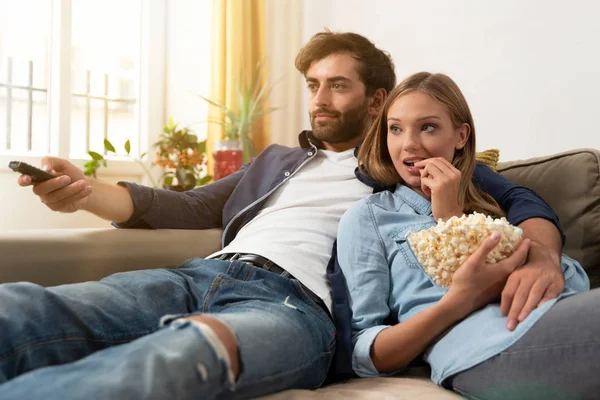 TV izlerken, bir koltukta evde patlamış mısır yemek çift