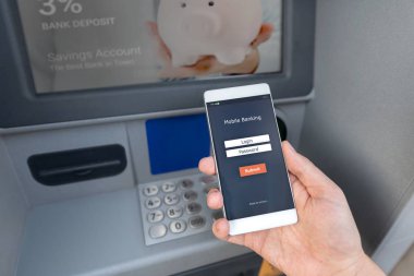 Bir kredi kartı kullanmadan bir Atm para çekmek. Bir telefon ile mobil bankacılık için bir giriş ekranı tutan kişi.