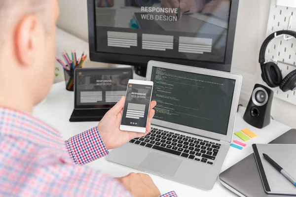 デザイナーは レスポンシブ Web デザイン プロジェクトに取り組んでいます Web 開発者とのオフィスでの机の上の現代装置を操作するプログラマ — ストック写真
