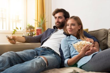 TV izlerken, bir koltukta evde patlamış mısır yemek çift