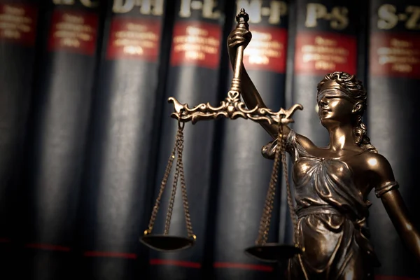 Lady justice, themis, statue of justice on books background. Law concept with justice figurine in library