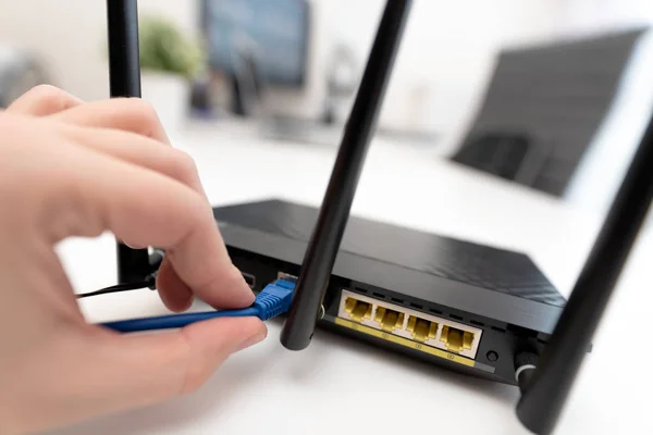 Ο άνθρωπος το internet καλώδιο συνδέεται με το router — Φωτογραφία Αρχείου