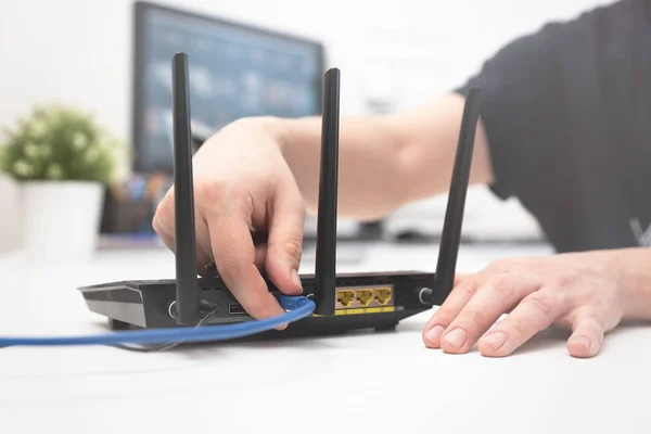 Człowiek łączy przewód internetowy do routera — Zdjęcie stockowe