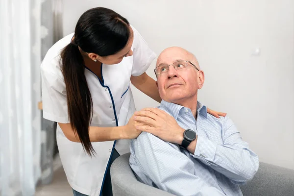 Glimlachende verpleegkundige en oude Senior man patiënt thuis — Stockfoto