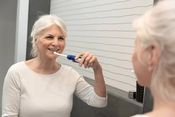 Elektrische Zahnbürste von Seniorin benutzt — Stockfoto